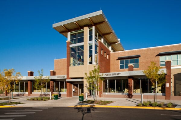 Modern public library building with large windows, brick and beige exterior, and a prominent entrance under a blue sky—an inspiring project from Bradbury Miller Associates (BMA).