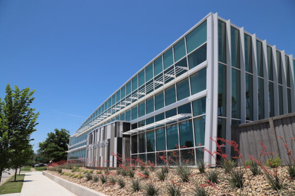 Modern glass and steel building with angular lines, landscaped with rocks and desert plants under a clear blue sky—a signature project by Bradbury Miller Associates (BMA).