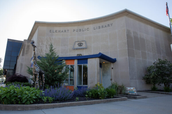 Exterior view of the Elkhart Public Library building, featuring a main entrance, landscaping, and a giraffe sculpture near the doorway—a project connected with Bradbury Miller Associates (BMA).