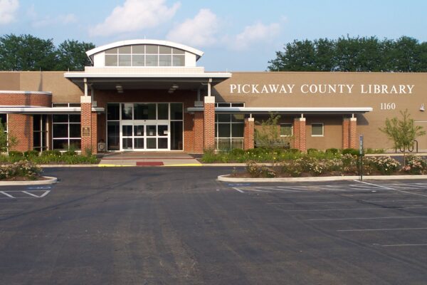 The front entrance of Pickaway County Library, a modern brick and glass building, stands proudly with a BMA (Bradbury Miller Associates) sign and parking lot in view.