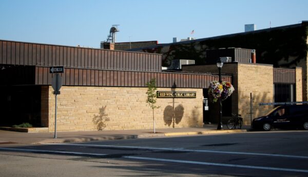 Exterior view of Red Wing Public Library, a low-rise brick building with a sign above the entrance, hanging flower baskets, and a bicycle parked near the door—an inviting space supported by Bradbury Miller Associates.