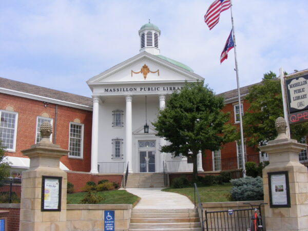 Front entrance of Massillon Public Library with steps, columns, two flagpoles, and a ramp; American and Ohio flags are visible. Photo courtesy of Bradbury Miller Associates (BMA).