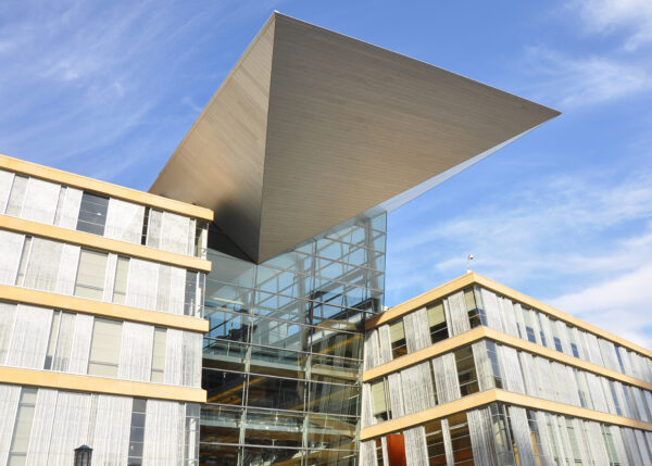 Modern building with large glass facade and a prominent triangular metal overhang extending above the entrance, set against a blue sky—a signature project by Bradbury Miller Associates (BMA).