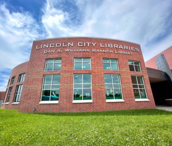 Exterior view of the Dan A. Williams Branch Library, part of Lincoln City Libraries, with large windows and a brick facade under a partly cloudy sky. Designed in collaboration with Bradbury Miller Associates (BMA).
