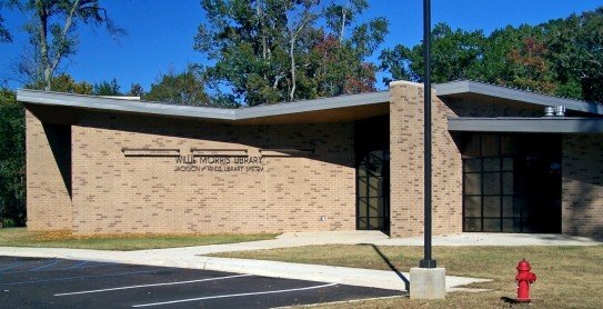 A single-story, modern brick building with large windows, labeled "Willis Morris Library Jacksonville Public Library Branch," sits near a parking lot and a red fire hydrant—an inviting space featured by Bradbury Miller Associates.