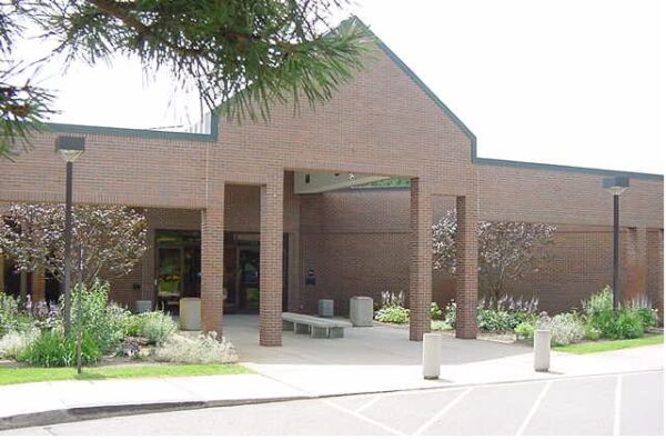 A single-story brick building with a peaked entrance, surrounded by landscaping, concrete benches, and parking spaces in front—an inviting design often featured by Bradbury Miller Associates (BMA).