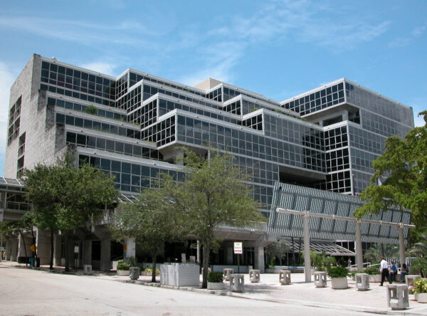 Large modern building with multiple glass-paneled levels and terraces, surrounded by trees and outdoor seating under a clear blue sky—a standout project that reflects the innovative style of Bradbury Miller Associates (BMA).