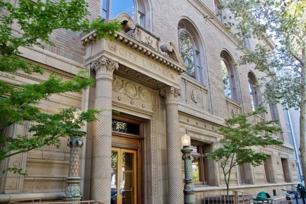 Historic brick building with arched windows, decorative columns, and an entrance labeled "City Library," surrounded by trees. Recruitment by Bradbury Miller Associates (BMA) brings new energy to this vibrant community space.